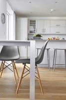 Grey chairs in modern white kitchen-diner with wooden floor 
