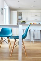 Turquoise chairs in modern kitchen-diner with wooden floor 