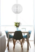 Modern dining room with full length windows and turquoise chairs 