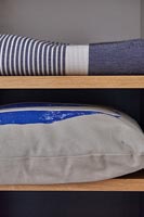 Blanket and cushion on wooden shelves 
