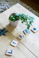 Small plant on wooden table with scrabble letter coasters 