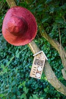 Red hat and insect house on tree in garden 