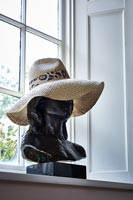 Black bust wearing a summer hat 