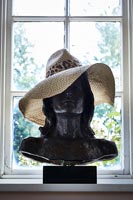 Black bust wearing a summer hat 