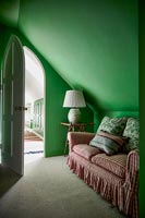 Red gingham sofa in green painted bedroom 