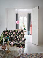 Black and floral patterned sofa in modern living room with view to dining room