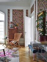 Colourful floral wallpaper and wicker rocking chair 