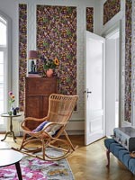 Colourful floral wallpaper and wicker rocking chair 