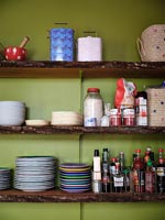 Wooden kitchen shelves against green painted wall 