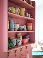 Pink painted shelves against pink painted wall in modern kitchen 
