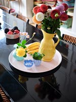 Yellow vase on pink tray on modern black dining table 