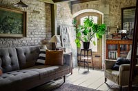 Large houseplant on stool in window of country living room 