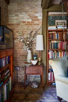 Bookshelves and side table in country living room with exposed brickwork 