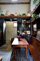 Wooden table and long bench in black painted country kitchen 