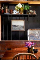 Shelf of ornaments in black painted wooden dining area 