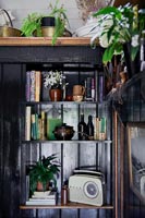 Black painted wooden unit with radio, books and ornaments 
