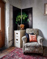 Floral armchair in corner of country living room with decorative wall panels 