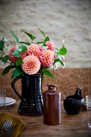 Flower arrangement in black jug on country dining table 