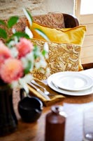 Floral cushions on seat next to country dining table 
