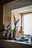 Bird feathers in vases and pots on windowsill 