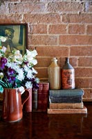 Books, vintage ceramic bottles and flowers in vase 