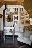 Armchair in country bathroom with framed paintings on exposed brick wall 