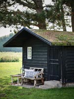Wooden summer house with living roof and rustic bench outside 
