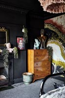 Vintage wooden chest of drawers in eclectic black painted bedroom 