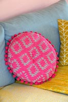 Bright pink cushion on blue and yellow sofa 