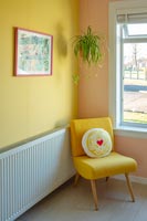 Yellow armchair in modern living room with colourfully painted walls. 