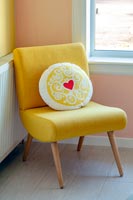 Heart patterned cushion on modern yellow chair 