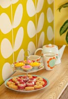 Cake stand with cakes and biscuits and teapot with matching cups 