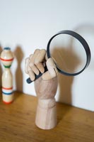 Wooden hand holding magnifying glass 