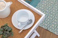 Teapot and cup on tray table with cork surface