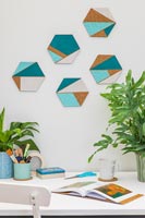 Hexagonal cork shapes with painted geometric areas used for wall decorations above desk