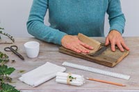 Woman sanding piece of wood with fine sandpaper