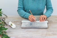 Woman using a ruler and pencil to mark wood