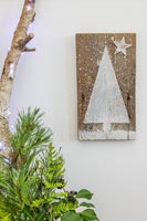 Christmas tree themed wall hanging made of wood decorated with paint and string fixed to wall