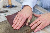 Woman sanding down piece of wood with fine sandpaper