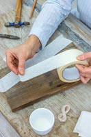 Woman using masking tape to mask a shape on wood ready for painting