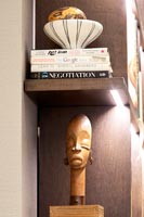 Wooden African carving on illuminated bookshelf 