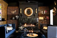 Black and gold living room with lit fireplace