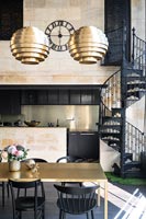 Gold and black dining room with view to modern kitchen and black wrought iron spiral staircase 