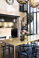 Black and gold modern dining room with view into kitchen and wrought iron spiral staircase 