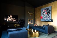 Black and gold modern bedroom with colourful artwork and large seating area