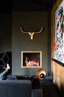 Fireplace and gold sculpture on dark grey wall of eclectic bedroom 