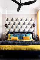 Black, white and yellow modern bedroom with patterned feature wall and ceiling fan