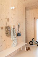 Timber clad modern hallway with large coat hooks and bench 