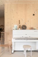 White upright piano in modern timber clad music room 