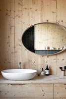 Large oval mirror above sink in wooden bathroom 